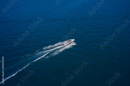 Top view of a white boat sailing in the blue sea. A boat with a motor on blue water. Aerial view luxury motor boat. Top view of the boat.