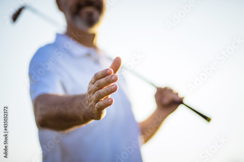 The golfer extends his hand.