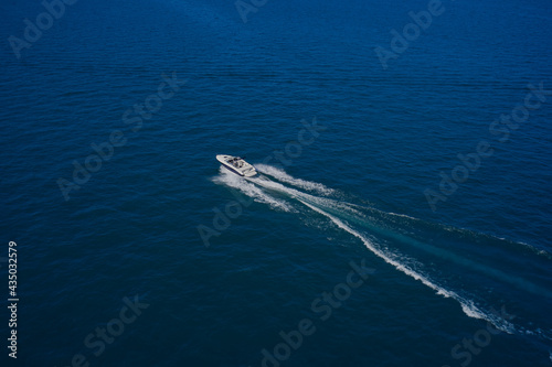 Top view of a white boat sailing in the blue sea. Aerial view luxury motor boat. A boat with a motor on blue water. Top view of the boat. © Berg