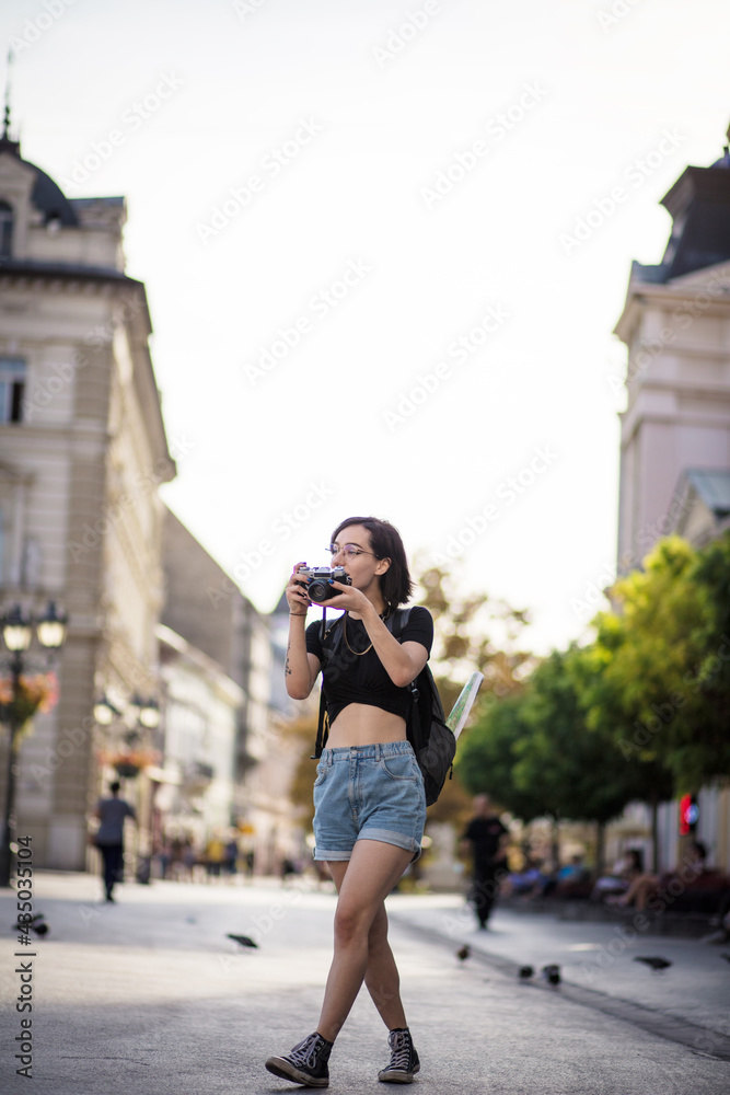  Young woman taking photo in the city with camera.
