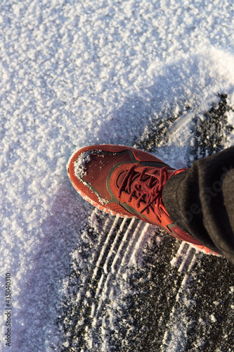 A boot on a background of snow-covered ice. The footprint of the sole in the form of lines. Scratched ice. The atmosphere of frost, cold and winter. Shifted focus, blurred edges.