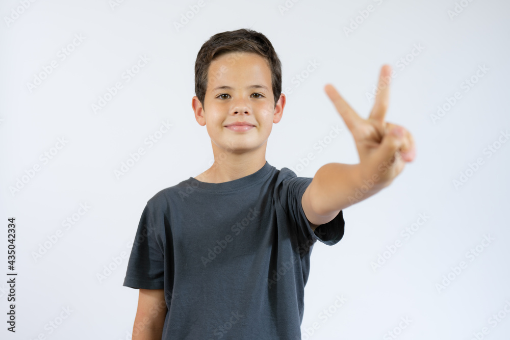 Portrait of little boy showing victory hand sign on white background Portrait of little boy showing victory hand sign on white background
