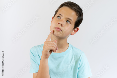 Portrait of cheerful boy with good idea - isolated over white background. 10 year old kid pointing finger up. Child points by finger upward. Cheerful boy shows something