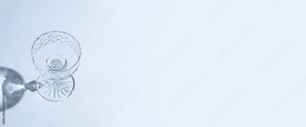 empty glass goblet on a blue background. Top view, flat lay. Banner empty glass goblet on a blue background. Top view, flat lay. Banner