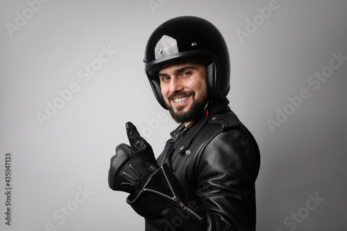 Portrait of bearded young male model wears biker helmet and leather jacket.