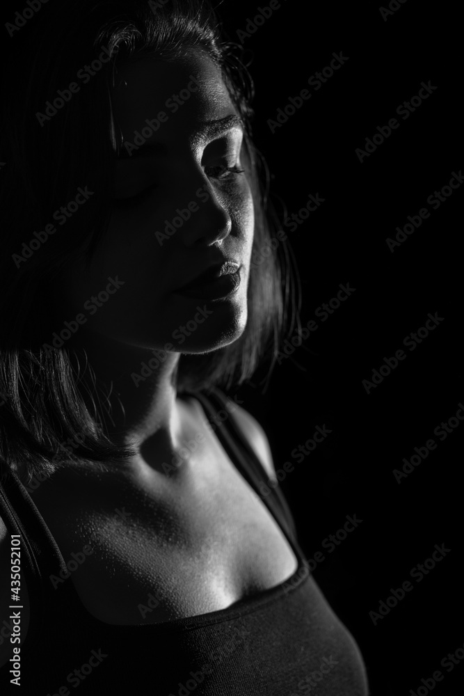Obraz premium Portrait of attractive a young woman with cinematic lighting. Woman wearing a suspender bodysuit. Half naked sexy woman. Vertical shot. Dramatic monochrome, black and white photo.