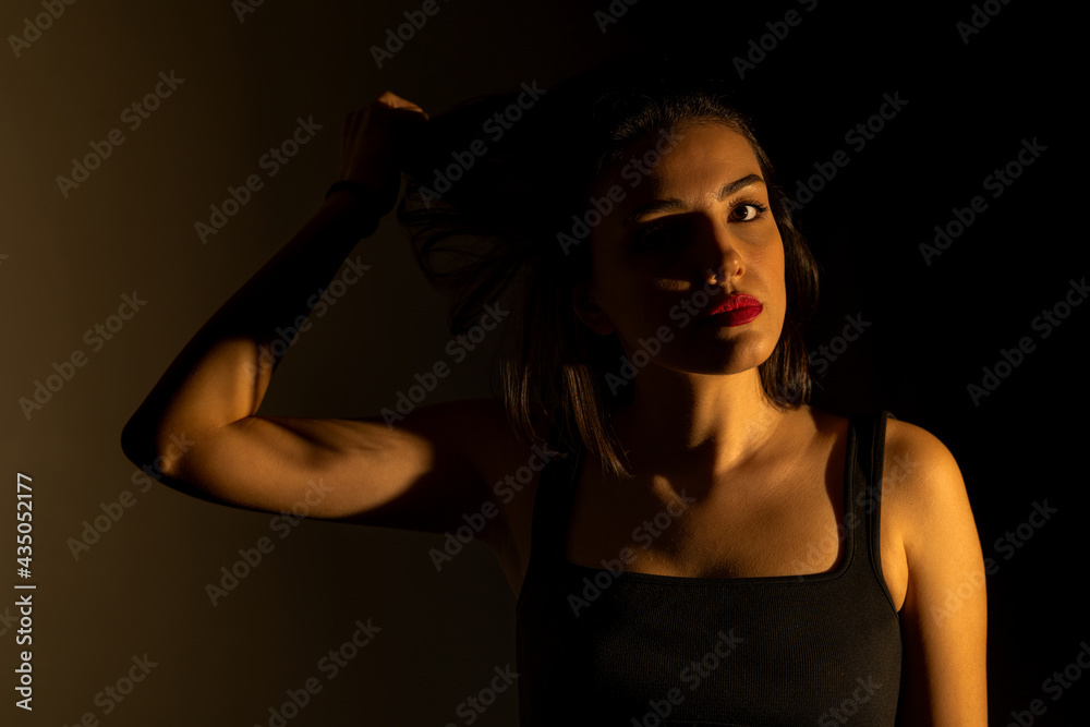 Portrait of attractive a young woman with cinematic lighting. Woman wearing a suspender bodysuit. Half naked sexy woman. Horizontal shot.