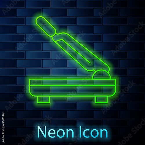 Glowing neon line Paper cutter icon isolated on brick wall background. Vector
