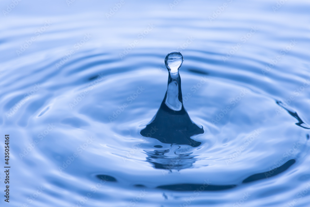 water drop splash in a glass blue colored shot of water that is dripping and reflecting water. water drop splash in a glass blue colored shot of water that is dripping and reflecting water.