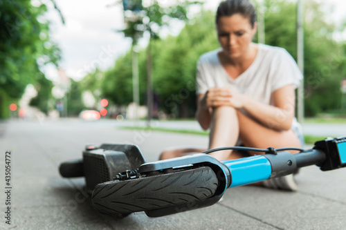 Young woman suffering from knee pain after e-scooter riding accident