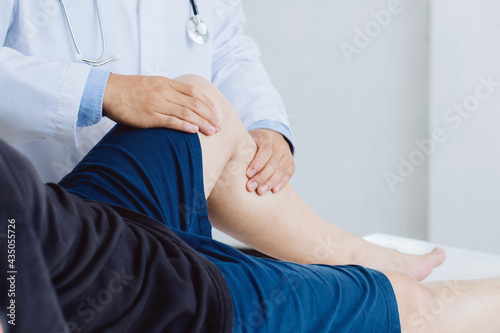 physiotherapist doctor working examining treating injured leg of male patient and giving exercising leg treatment male patient in physio clinic .