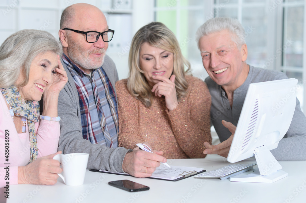 two senior couples sitting at table and working two senior couples sitting at table and working