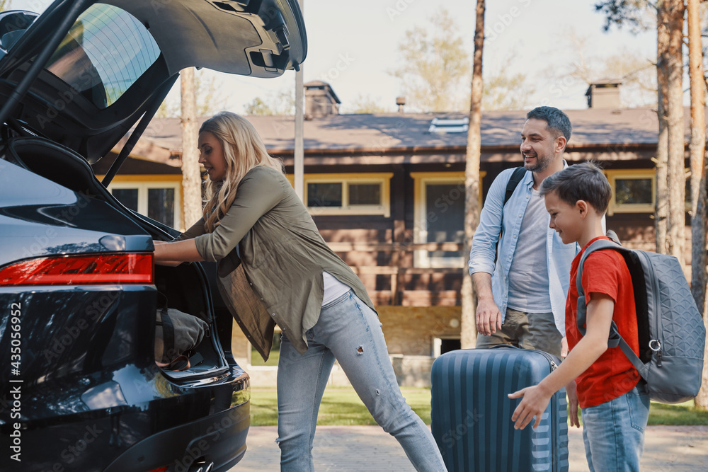 © gstockstudio - Happy family packing stuff in car and smiling while standing in front of the house © gstockstudio - Happy family packing stuff in car and smiling while standing in front of the house