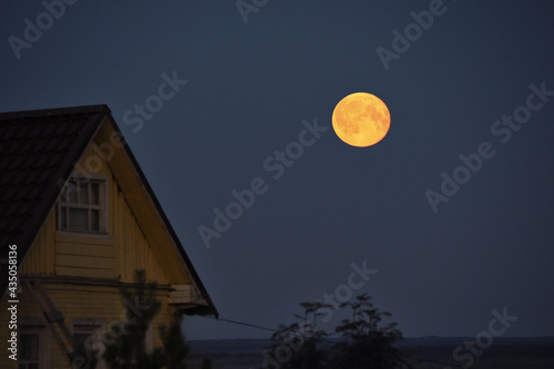 Full moon in the night sky over the roof of the house