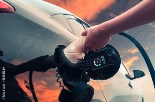 EV car charging power hybrid electric car at the charging station with graphical electronic function evening sunset, environmental friendly transportation vehicle automobile traveling commuting.
