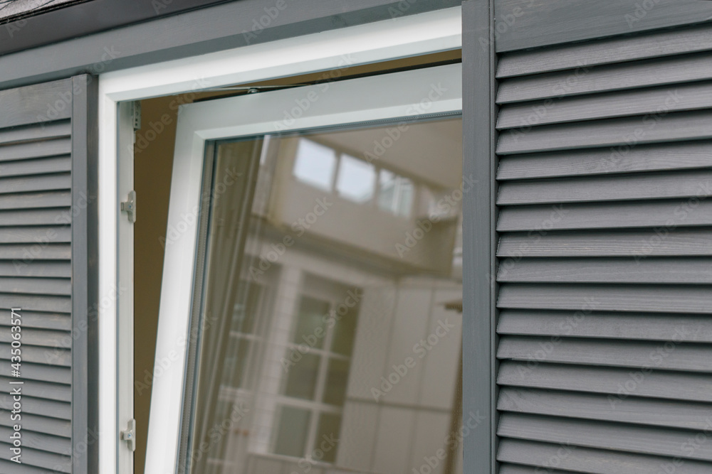Metal-plastic window is ajar. Wooden shutters-lattices. Close-up. Concept of airing the premises, at home. Metal-plastic window is ajar. Wooden shutters-lattices. Close-up. Concept of airing the premises, at home.