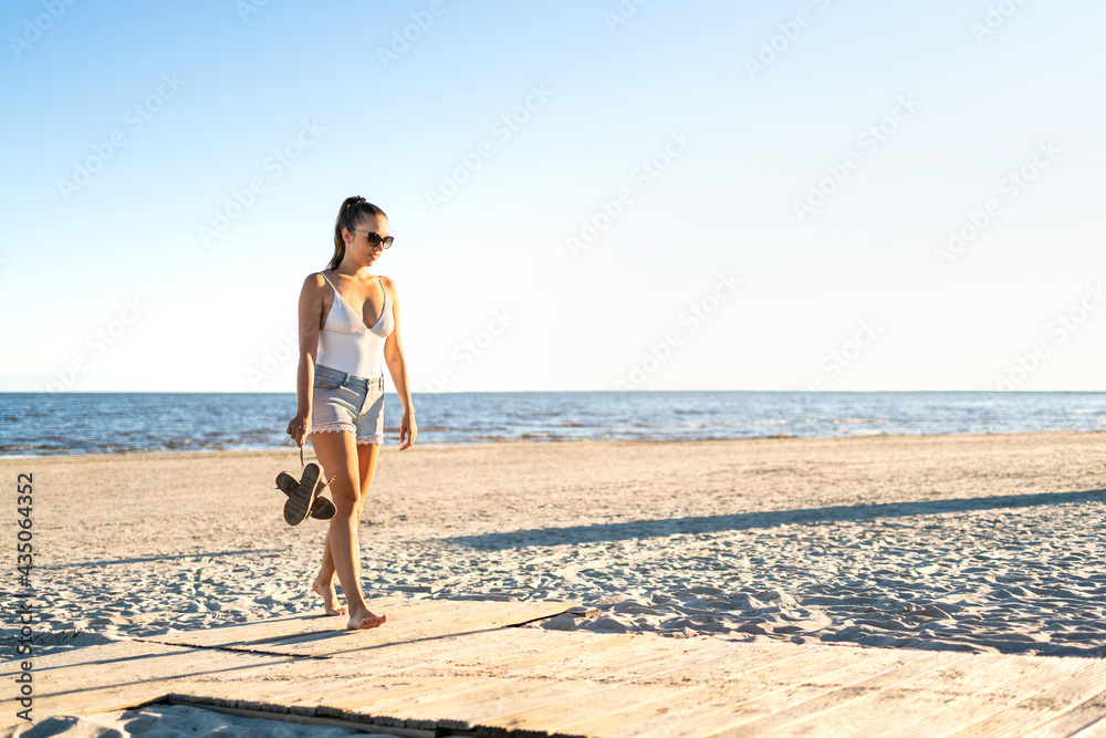Thoughtful lonely woman walking at an empty beach. Thinking about life at the peaceful quiet sea. Pensive sad single girl leaving. Broken heart, melancholy, loneliness or lost hope. Silent calm summer