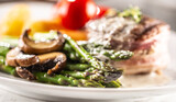 Grilled steak served on a plate with asparagus, mushrooms and sauce