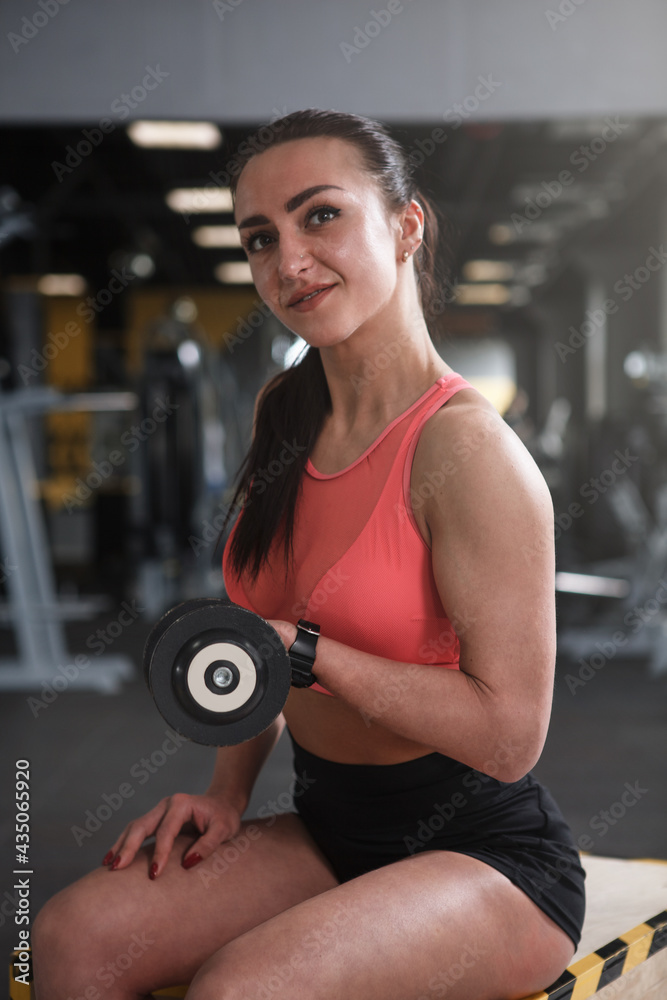 Cheerful female weightlifter exercising with dumbbells at the gym Cheerful female weightlifter exercising with dumbbells at the gym