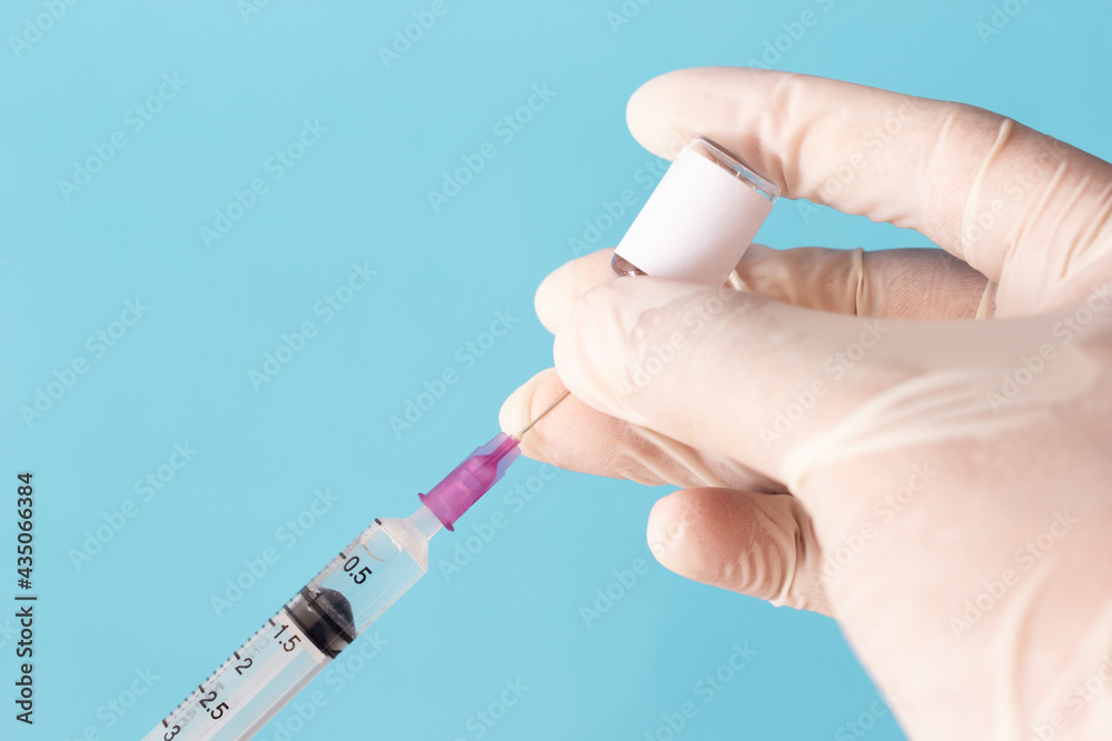 A close up of the vaccine and the syringe in the doctor's hand A close up of the vaccine and the syringe in the doctor's hand