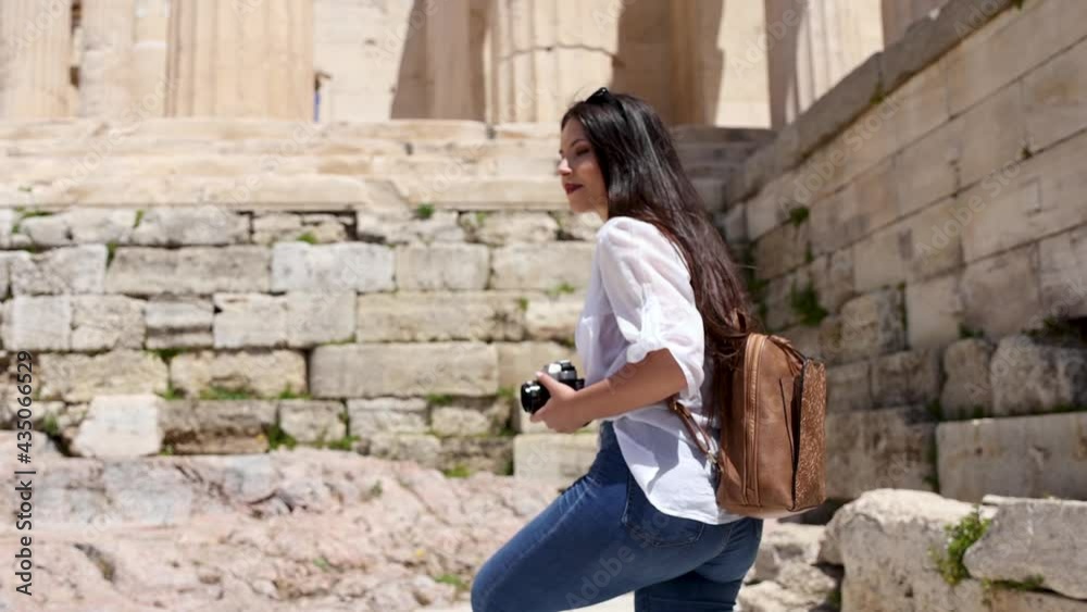 A tourist woman on summer vacations walks up to the Parthenon Temple at the Acropolis of Athens, Greece A tourist woman on summer vacations walks up to the Parthenon Temple at the Acropolis of Athens, Greece