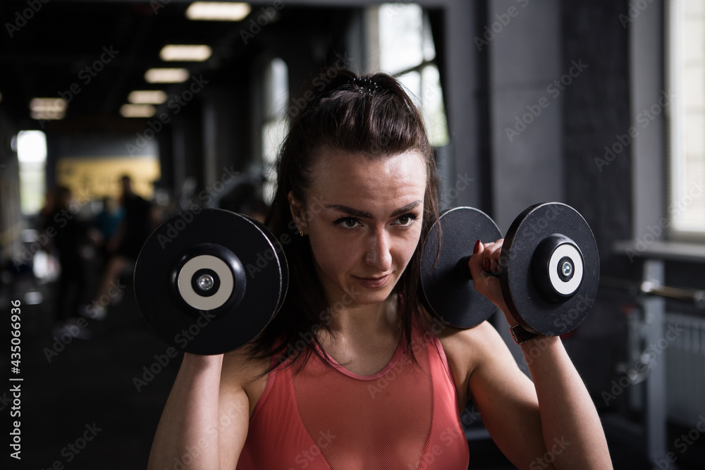 Close up of a focused female athlete exercising with dumbbells Close up of a focused female athlete exercising with dumbbells
