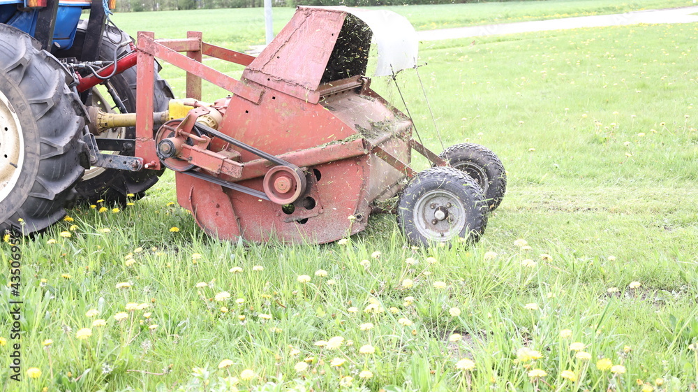 Obraz premium the blue tractor pulls the old red grass cutter