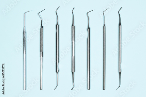 Some medical dental tools on light blue background. Flat lay closeup top view on dental instruments. Dental probes and explorers
