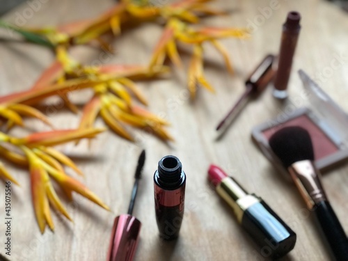 Set of makeup,cosmetics,Red matte lipstick and beautiful Heliconia flowers bouquet on wood background,with natural dimly light,free space for your text design,selective focus.