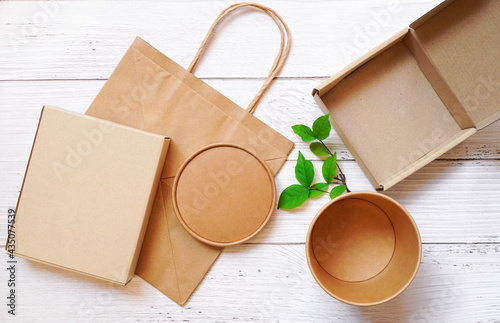 Wallpaper Mural Top view of Paper box packaging in rectangle and round shape and paper bag with green leaves on white wooden background , delivery eco package and save environment  concept Torontodigital.ca