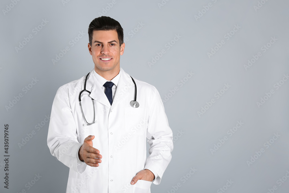 Happy male doctor offering handshake on light grey background. Space for text Happy male doctor offering handshake on light grey background. Space for text