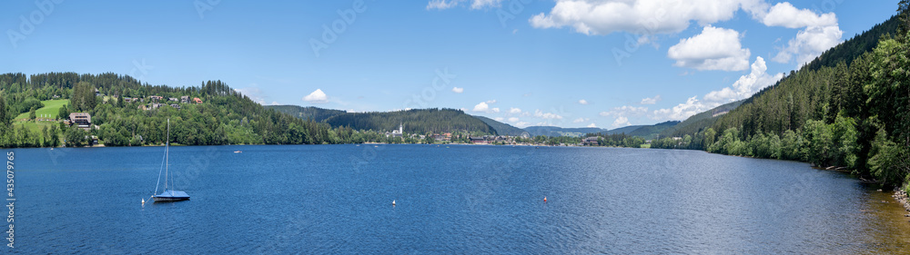 Titisee mit Boot - idyllisches Panorama im Schwarzwald, Deutschland - Blick vom Ostufer über den See zum Ort Titisee