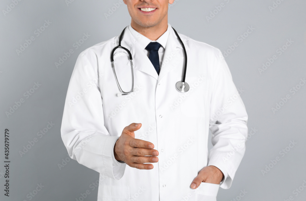 Happy male doctor offering handshake on light grey background, closeup Happy male doctor offering handshake on light grey background, closeup