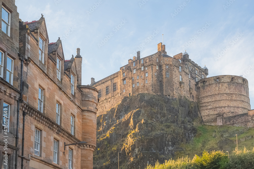 View from Grassmarket of the iconic medieval hilltop Edinburgh Castle in the historic Scottish old town of Edinburgh, Scotland during golden hour on a summer evening.