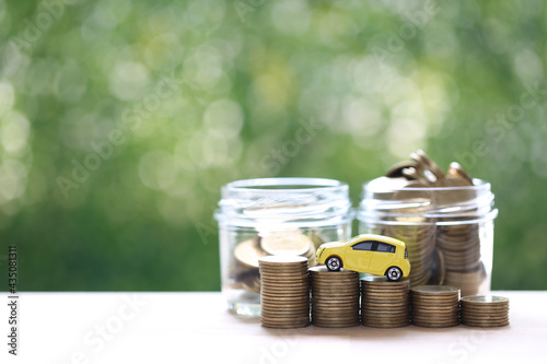 Miniature car model on growing stack of coins money on nature green background, Saving money for car, Finance and car loan, Investment and business concept