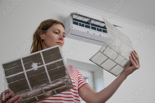 Schilderij op canvas Woman replacing old dusty air filter with new one on air conditioner