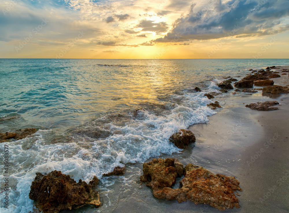 Rocky shoreline of Caspersen Beach in Venice Florida USA with a yellow orange sunset over the Gulf of Mexico