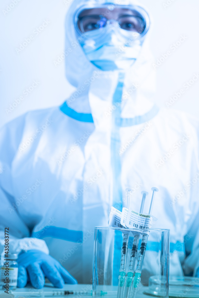 Focus on vaccine against Coronavirus COVID-19. Syringes label in the medical cup with antivirus on the medical worker table. Cure from respiratory syndrome strain of Corona virus. Ready to use shot.