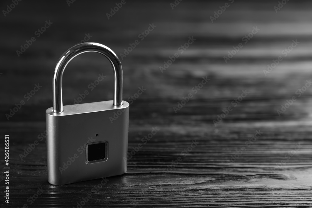 Naklejka premium Modern padlock on black wooden table. Space for text