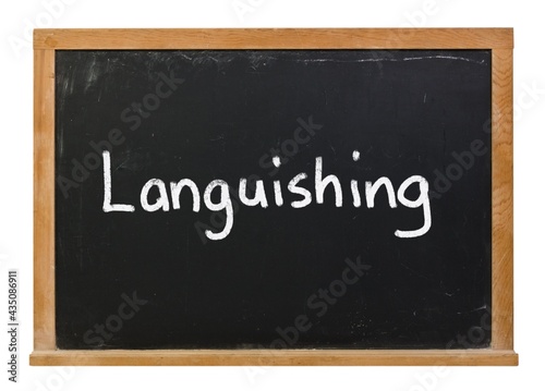 Languishing written in white chalk on a black chalkboard isolated on white