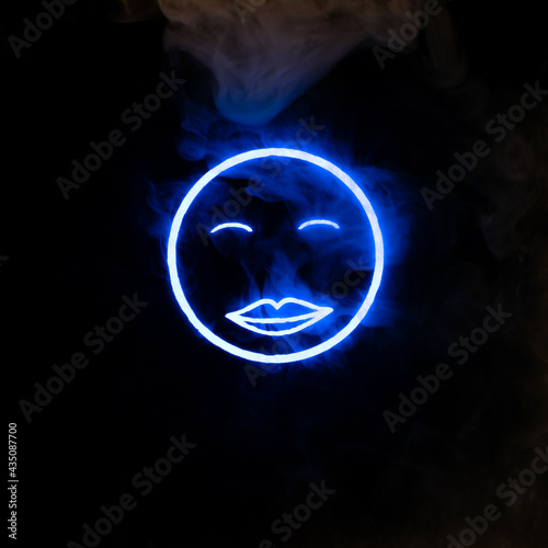 Stylized face expressing emotion glows through the stream of smoke in the dark