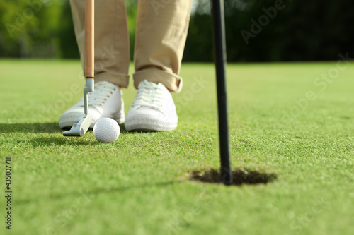 Person playing golf on green course, closeup