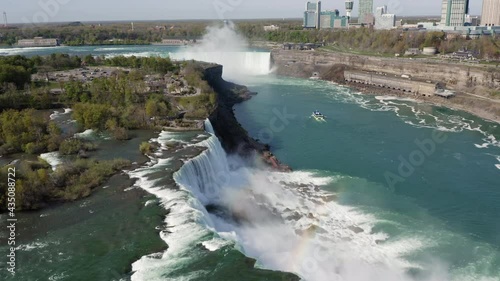 Flying above the edge of iconic Niagara Falls and small boat on Niagara River photo