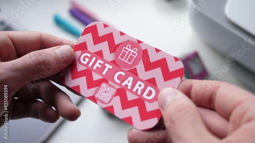 Holding a gift card with a QR code on it in the hands. Closeup shot