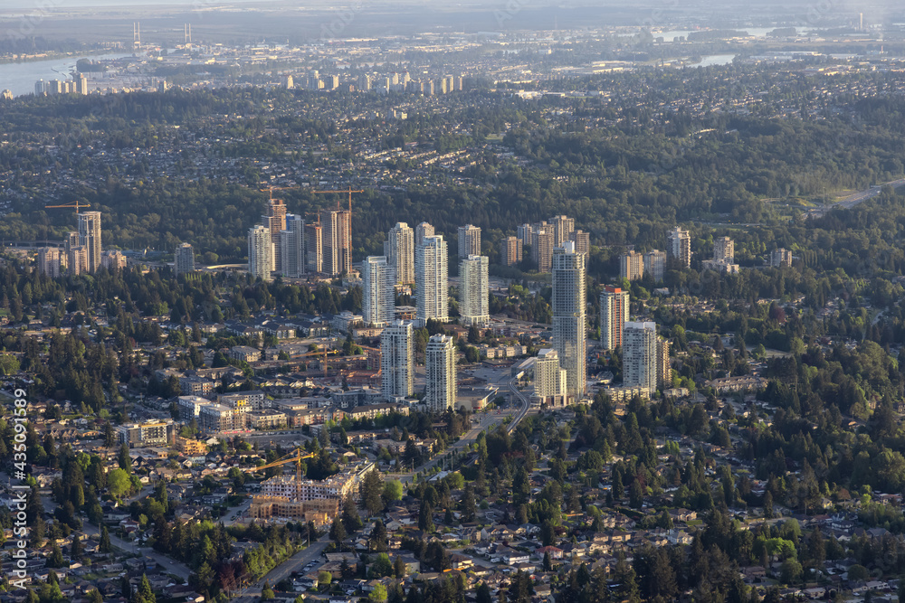 Aerial View from Airplane of Residential Homes and Buildings in a modern city during sunny evening. Taken in Coquitlam, British Columbia, Canada.