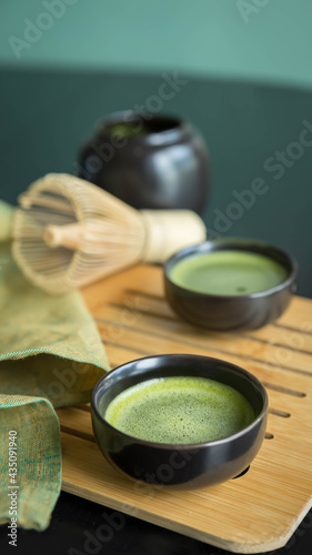 Green matcha tea in a traditional cup on a bamboo tablet and green napkin . Trendy beverage . 