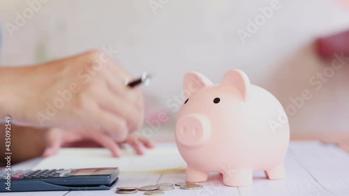 Close up of man putting a coin inside the piggy bank as saving or investment