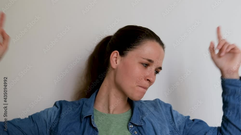 Young Caucasian European girl in shirt dances widely waving both hands and does not hide her joy and happiness. 4k footage of dancing human on white background in studio. Young Caucasian European girl in shirt dances widely waving both hands and does not hide her joy and happiness. 4k footage of dancing human on white background in studio.