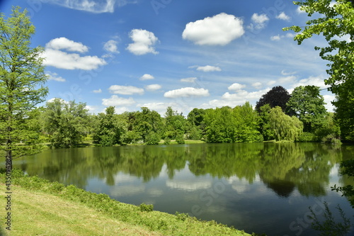 Le petit étang Tenreuken entouré de végétation luxuriante sous des cumulus de beau temps à Watermael-Boitsfort 