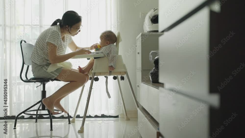 Happy Smiling Asian Young Mother enjoying feeding to her Little cute baby Happy Smiling Asian Young Mother enjoying feeding to her Little cute baby